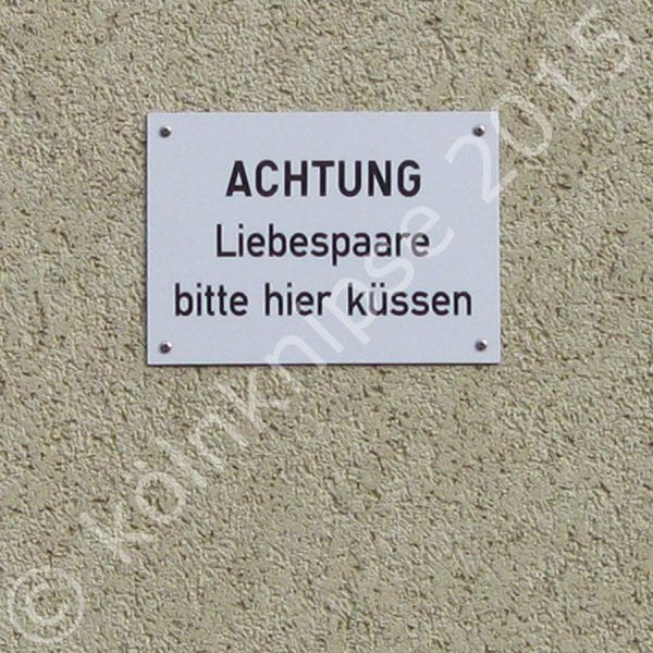 Fassade mit Schild: Achtung Liebespaare bitte hier Küssen